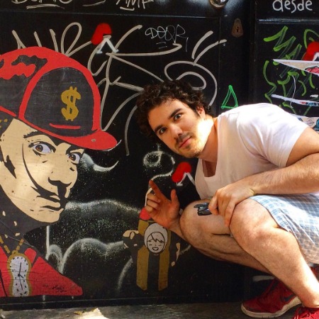 Kyle Kaminsky posing in front of wall painting.